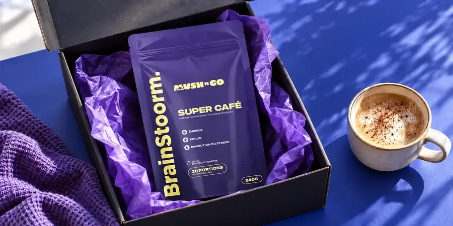Külföldről érkezett nyitott csomag lila selyempapírral, benne Mush N Go Brainstoorm tasak, mellette kakaós latte kék háttér előtt